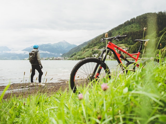 Muž stojí pri jazere a na ceste má odstavený bicykel